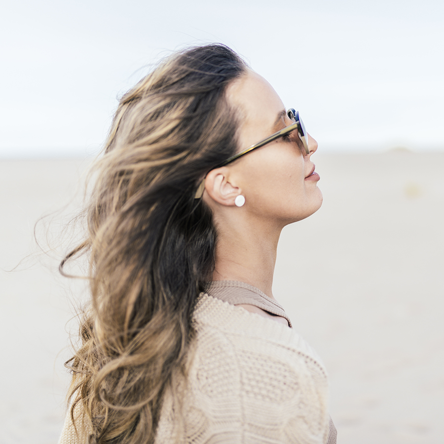 Woman wearing porcelain studs and sunglasses on a beach